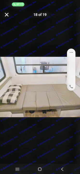 RV rental interior featuring a gray convertible bench seat with plaid pillows, extended for sleeping, next to a window.. Keystone RV Hideout 2022
