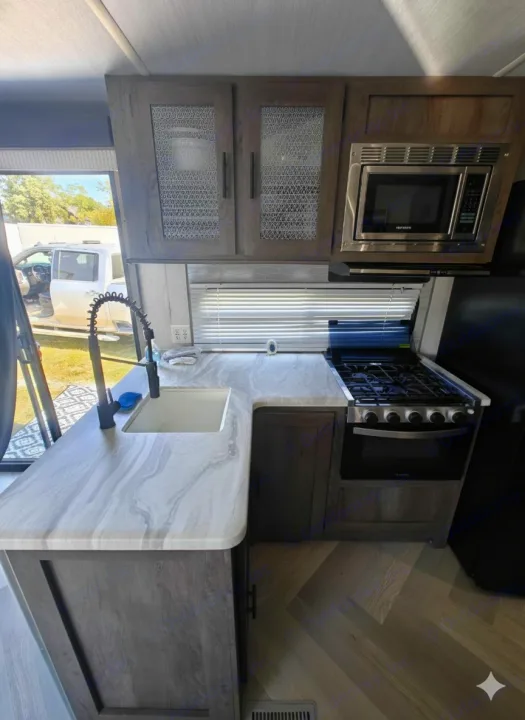 Explore this sleek RV rental kitchen: light countertops, sink, gas range, and microwave. Modern comfort on the go.. Salem 36VBDS 2021