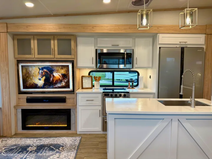 This modern RV rental interior showcases a fully equipped kitchen, a comfortable living area with TV, and a cozy fireplace.. Alliance RV Avenue 2023
