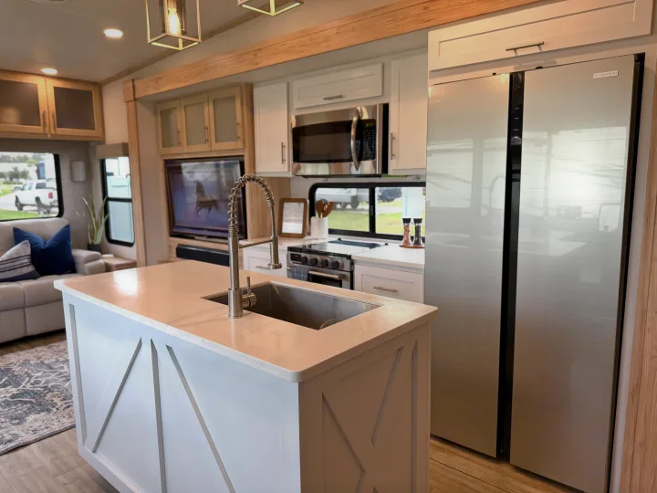 Bright, modern RV rental kitchen & living space. Features a large island, stainless appliances & comfy couch.. Alliance RV Avenue 2023