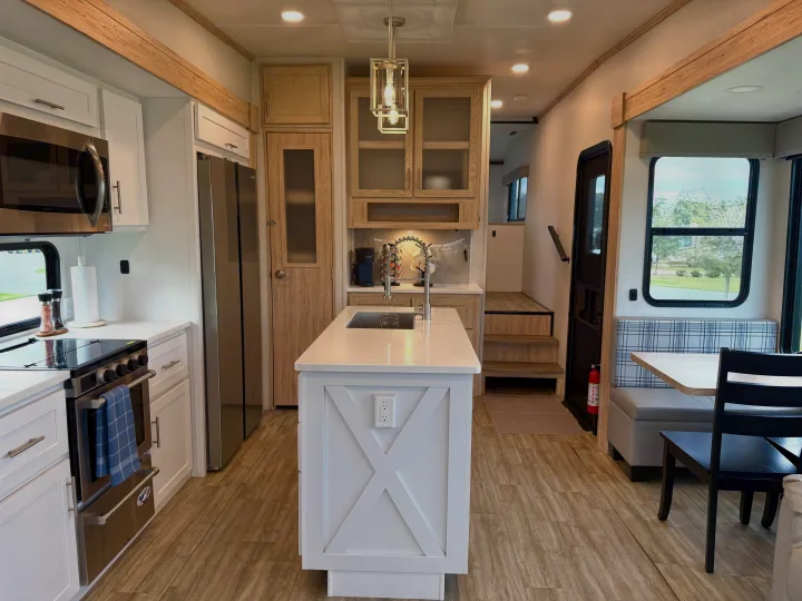 Bright, modern RV rental kitchen and dining area with a white island, stainless steel appliances, and a cozy dining nook.. Alliance RV Avenue 2023
