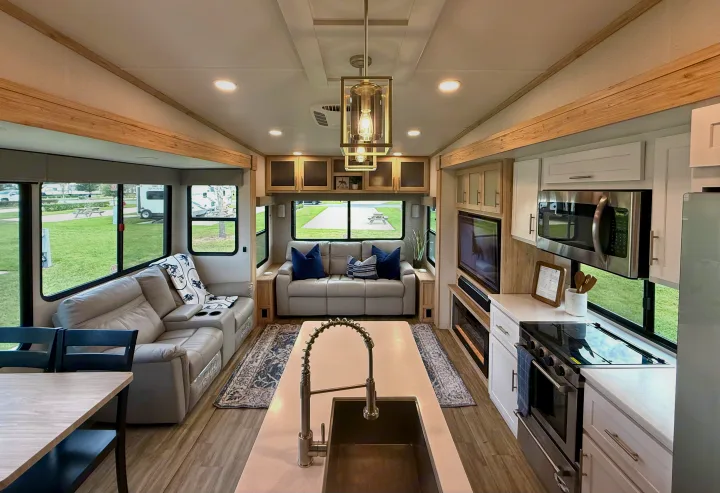 Spacious RV rental interior featuring a modern kitchen, comfortable living area, and large windows with campsite views.. Alliance RV Avenue 2023