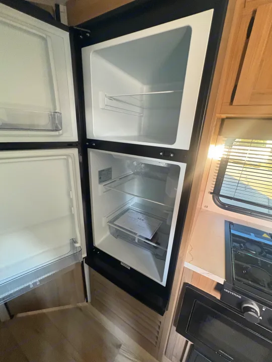 Ready for your RV rental adventure: a spacious, empty two-door refrigerator/freezer, with an RV kitchen nearby.. Keystone RV Coleman 2025