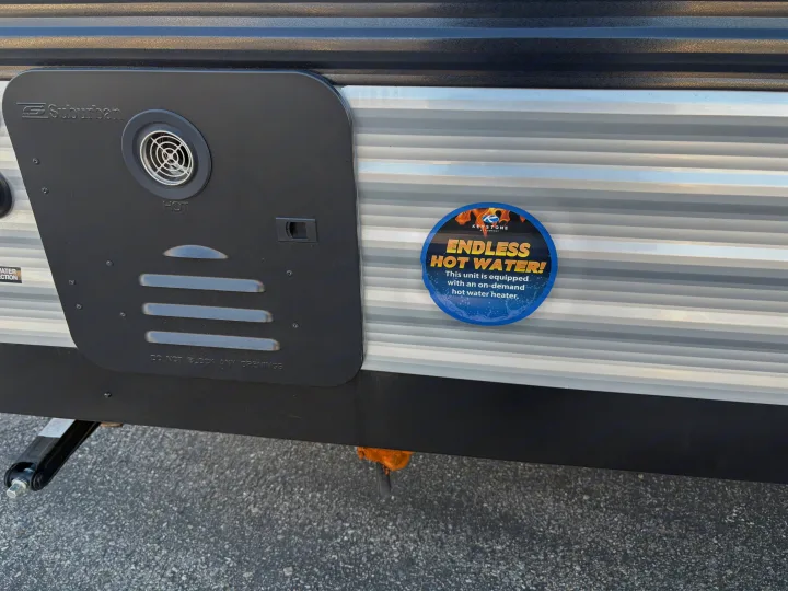 RV rental exterior: a Suburban on-demand hot water heater cover & "Endless Hot Water!" sticker. Enjoy continuous hot water!. Keystone RV Coleman 2025