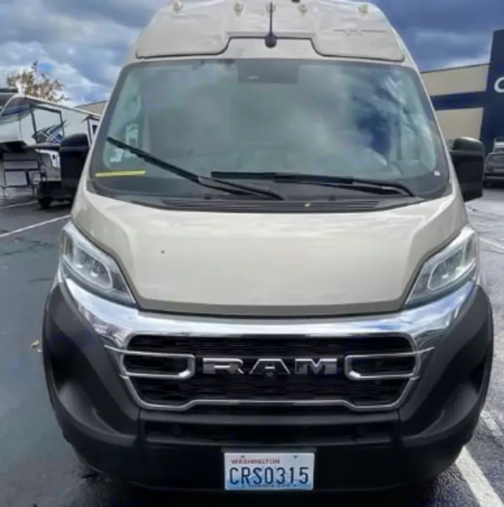 Front view of a light tan Ram ProMaster camper van, a potential RV rental, with Washington license plate CRS0315.. Winnebago Solis 2025