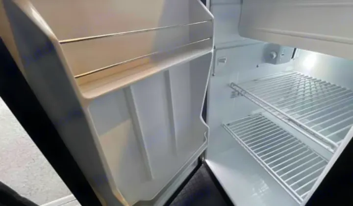 Clean, empty refrigerator in an RV rental, featuring wire shelves and door storage, ready for your journey.. Winnebago Solis 2025