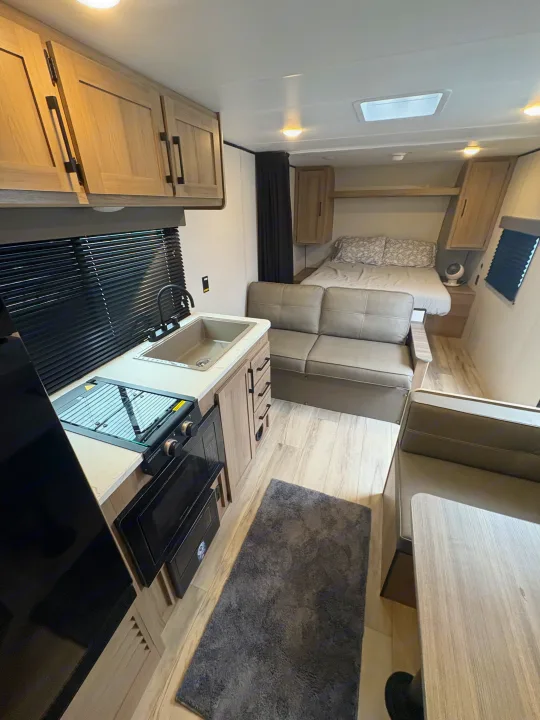 Modern rv rental interior with kitchen, bedroom, and living area featuring a sofa and dinette. Ready for travel!. Keystone RV Coleman 2025