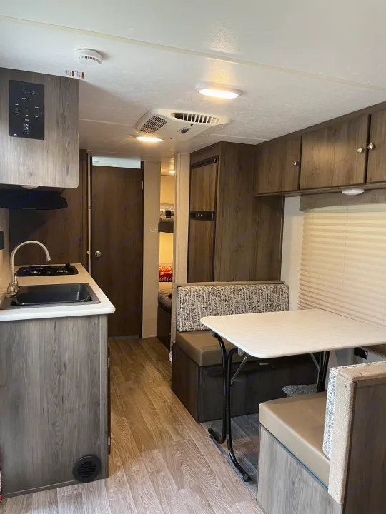 Explore this rv rental's modern interior featuring a compact kitchen, dinette with patterned cushions, and wood-look cabinetry.. Coachmen Viking Saga 21SBH 2019