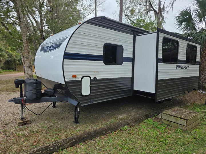 This Gulf Stream Kingsport travel trailer RV rental is ready for adventure, parked at a scenic campsite with its slide-out extended.. Gulf Stream Kingsport 2022