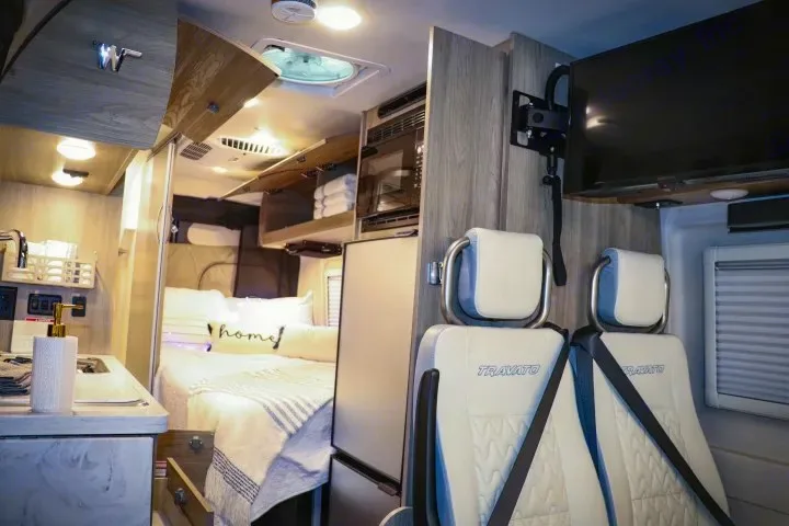 This rv rental features a cozy bedroom, kitchenette with fridge & microwave, TV, and passenger seats in a compact, well-designed interior.. Winnebago Travato 2022