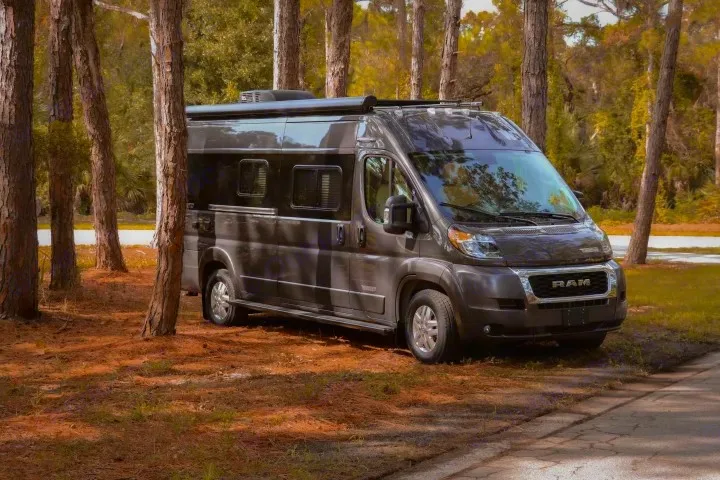This Ram ProMaster camper van rv rental, parked in a scenic forest, offers memorable outdoor travel experiences.. Winnebago Travato 2022