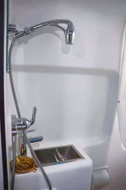 Compact RV rental wet bath, featuring an integrated shower, faucet, and small sink. Ideal for travel.. Winnebago Travato 2022