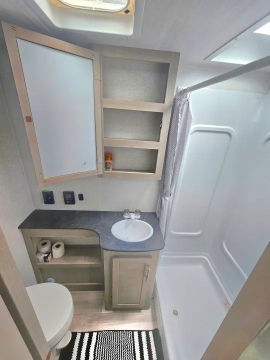 Compact and clean RV rental bathroom with a toilet, sink, vanity, medicine cabinet, and shower for comfortable travel.. Keystone RV Springdale 2024