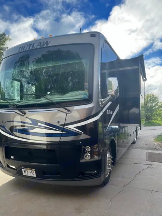 Stylish gray and black Outlaw rv rental motorhome with an extended slide-out, parked and ready for your adventure.. Thor Outlaw 2017