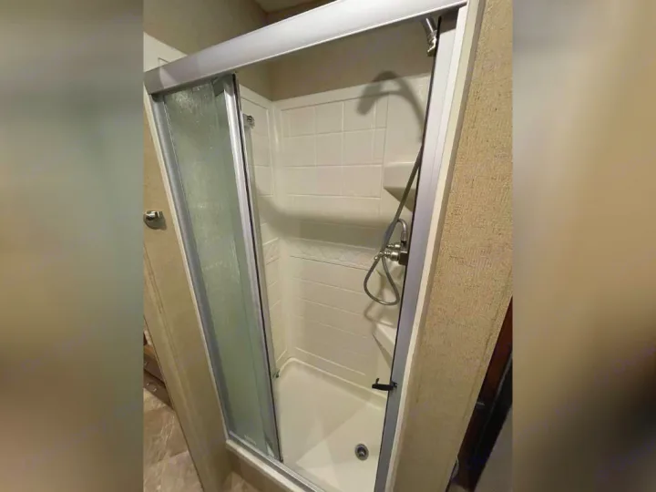 RV rental: Clean shower enclosure with a sliding glass door, white interior, and handheld shower head.. Thor Outlaw 2017