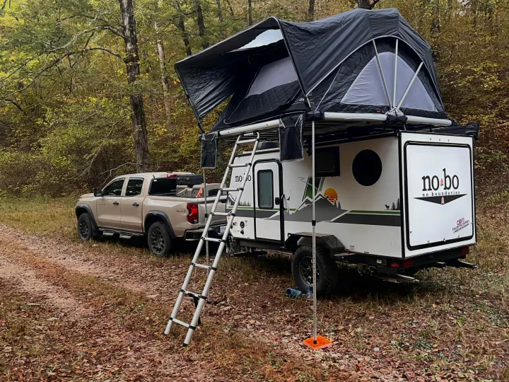 RV rental: No Bo camper with rooftop tent & ladder, towed by a pickup in a woodsy campsite.. Forest River NoBo 10.7 2024