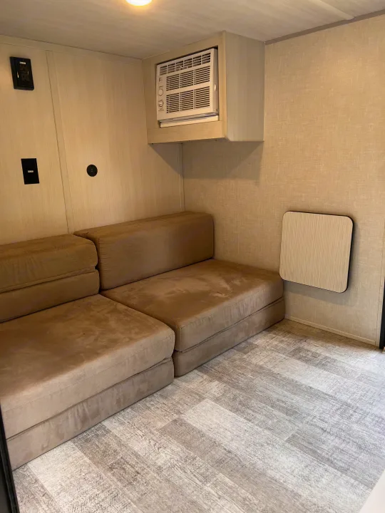 This cozy RV rental features a modular sofa, AC unit, wall outlets, and a foldable table, ideal for compact mobile living.. Forest River NoBo 10.7 2024
