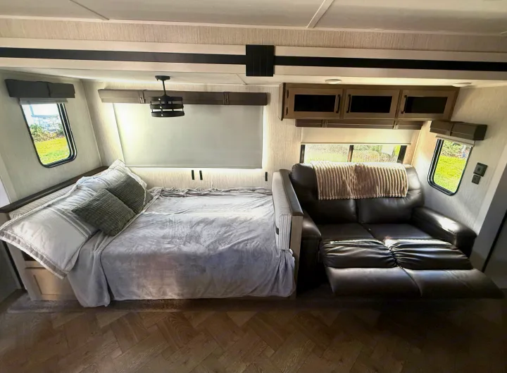 Inside this RV rental: a plush bed ready for rest and a comfy reclining sofa in a compact, well-appointed living space.. Forest River Palomino Puma 2022