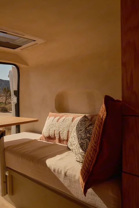 Cozy rv rental interior with desert views. Bench seating, warm light, and comfy cushions create an inviting camper van space.. Dodge Ram 1500 2021