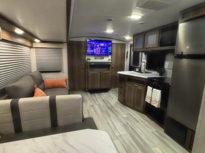 This modern rv rental interior features a cozy living area, full kitchen, and dining space with stylish light wood and gray tones.. Cruiser RV MPG 2023