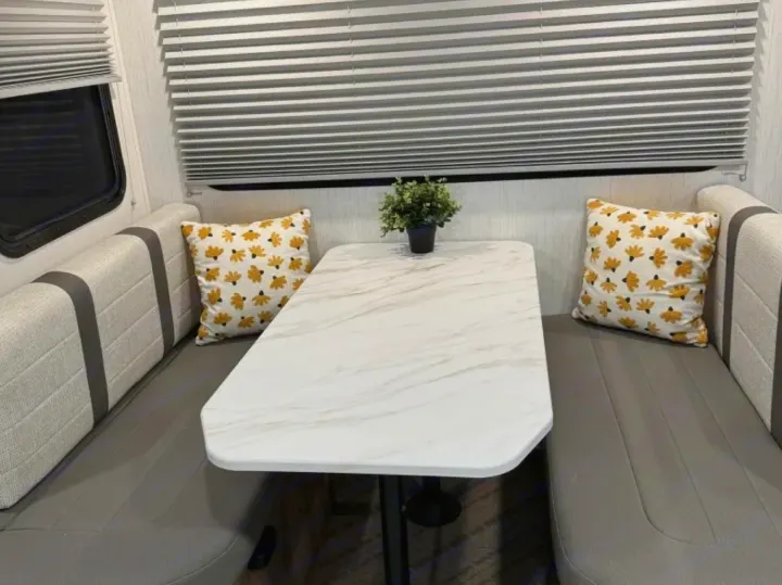 This RV rental features a modern dinette with comfortable bench seating, a stylish marble-look table, and playful floral pillows.. Cruiser RV MPG 2023