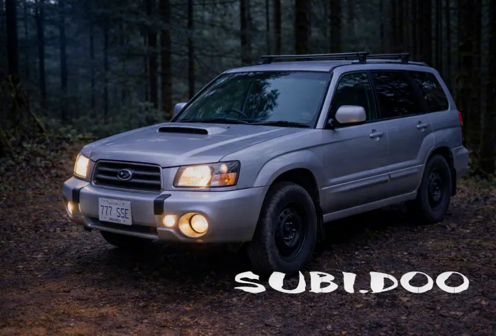 A silver Subaru Forester SUV, lights on, parked in a dark forest. Perfect for adventure, a rugged rv rental alternative.. Subaru Forester 2007