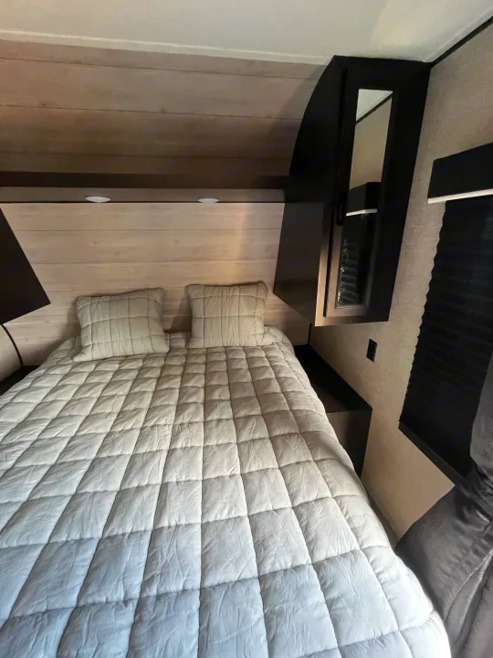 Cozy RV rental bedroom featuring a queen bed with a light grey quilted comforter and modern built-in storage.. Jayco Jay Flight SLX Rocky Mountain Edition 2022