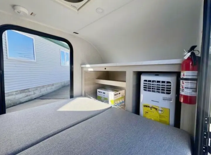 Cozy rv rental interior: bed, built-in storage, portable AC, and fire extinguisher for a safe, comfortable sleeping area.. Bontrager Outdoors 12RAD 2025
