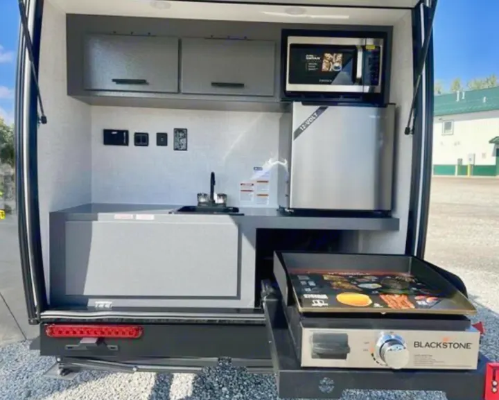 Explore this RV rental's rear outdoor kitchen: microwave, 12-volt fridge, sink, and Blackstone griddle for convenient camping.. Bontrager Outdoors 12RAD 2025