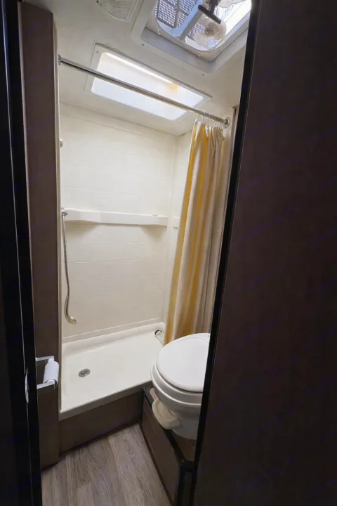 Inside this RV rental: a compact bathroom with a standing shower, toilet, and ceiling fan for your travels.. Thor Majestic 2018