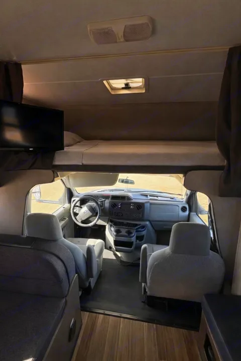 Spacious rv rental interior features a driver's cabin, overhead bed, and seating area, ready for your next road trip adventure.. Thor Majestic 2018