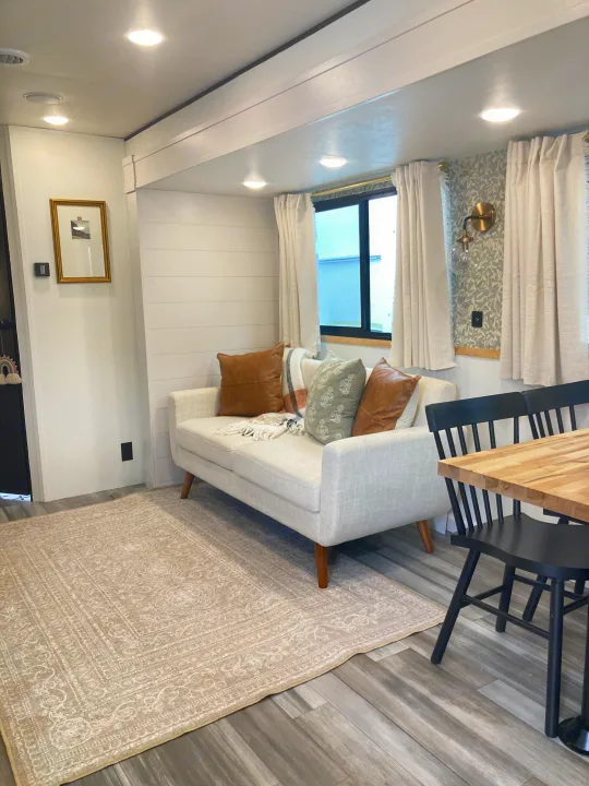 Cozy RV rental interior with modern decor, featuring a light sofa, patterned rug, and dining nook.. Jayco Jay Flight SLX 2025