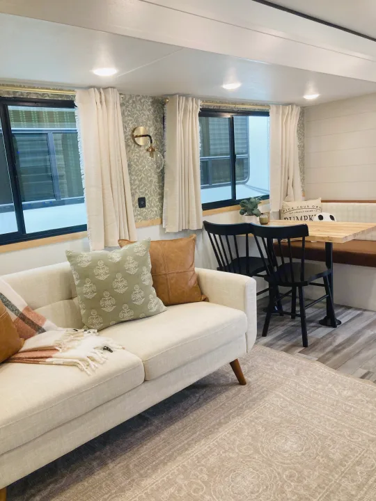 A modern & cozy RV rental interior with a sofa, patterned rug, and dining nook, offering comfortable travel living.. Jayco Jay Flight SLX 2025