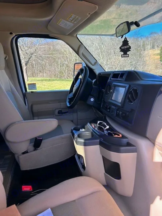Explore this RV rental's inviting cockpit, featuring a functional dashboard, comfortable front seats, and scenic views outside.. Thor Freedom Elite 2021
