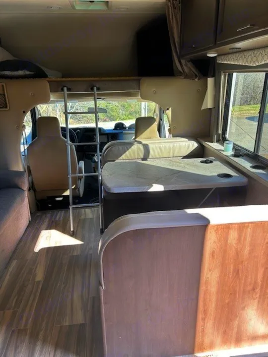 Inside a comfortable rv rental, showing the dinette, cab-over bed with ladder, and front cockpit. Ideal for travel.. Thor Freedom Elite 2021