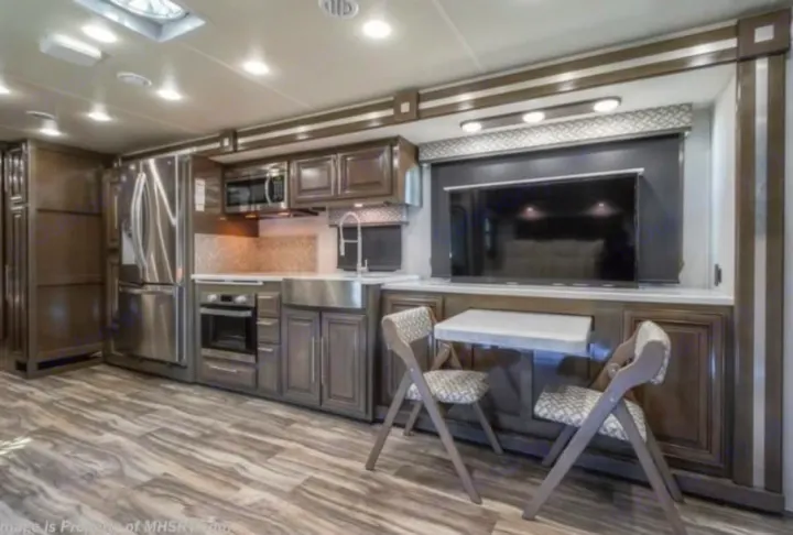 Spacious, modern RV rental interior with a full kitchen, stainless steel appliances, TV, and dining area, perfect for travel.. Georgetown GT7 2022