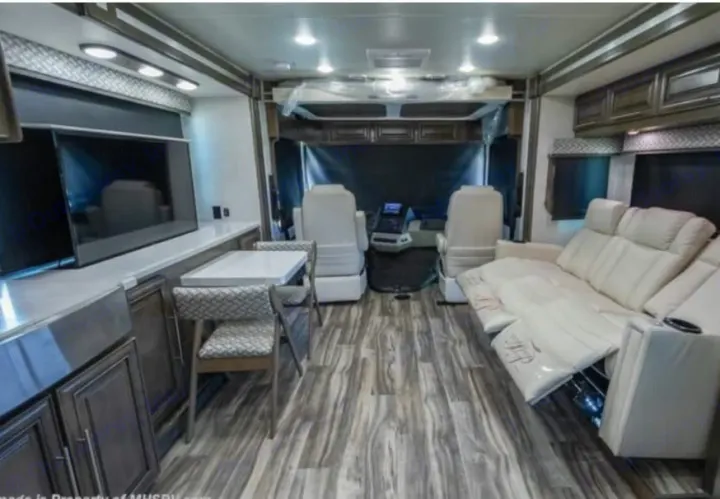 Explore this luxurious rv rental interior featuring a modern kitchen, dining table, reclining sofa, and cockpit.. Georgetown GT7 2022