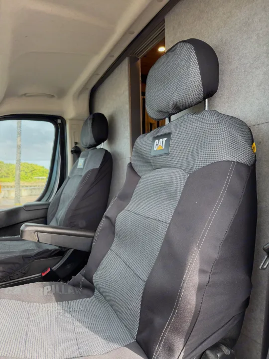 RV rental van interior: custom grey and black Caterpillar seat covers, featuring textured fabric and armrests for comfort.. Gmc Ram Promaster 2018