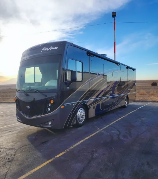 Explore the open road! This dark RV rental, with its unique graphic design, is parked on asphalt under a blue sky.. Fleetwood Pace Arrow 35E 2019