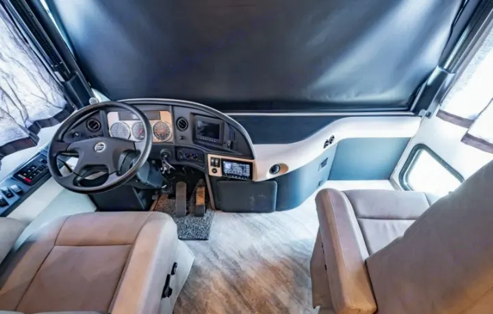 Interior view of a modern RV rental cockpit, featuring the steering wheel, dashboard, and two comfortable captain's chairs.. Fleetwood Pace Arrow 35E 2019