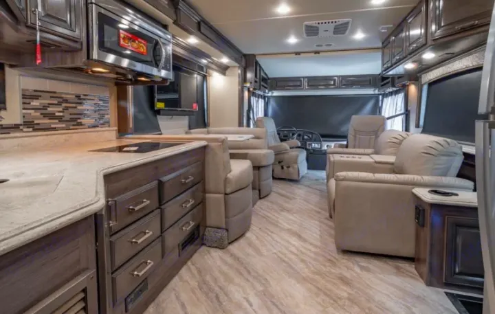 Spacious, modern RV rental interior featuring a full kitchen, comfortable lounge seating, and cockpit view.. Fleetwood Pace Arrow 35E 2019