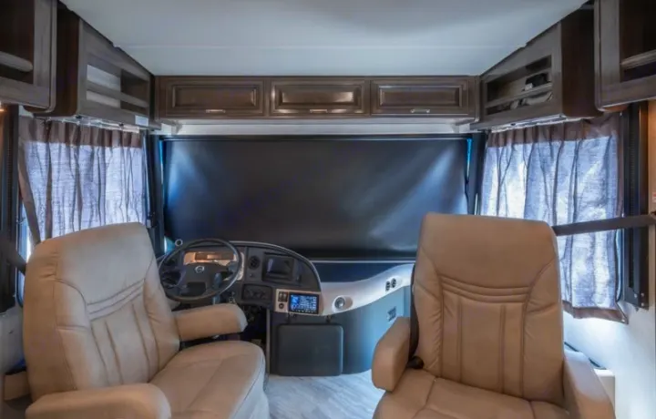 RV rental's front cockpit features two comfortable captain's chairs, steering wheel, dashboard, and overhead storage.. Fleetwood Pace Arrow 35E 2019
