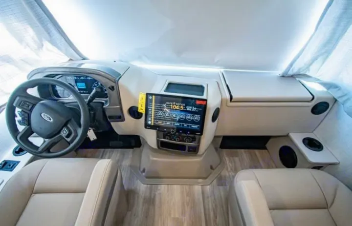Inside a modern RV rental: driver's cockpit with Ford steering wheel, digital dash, and large touchscreen display.. Axis 24.1 2027
