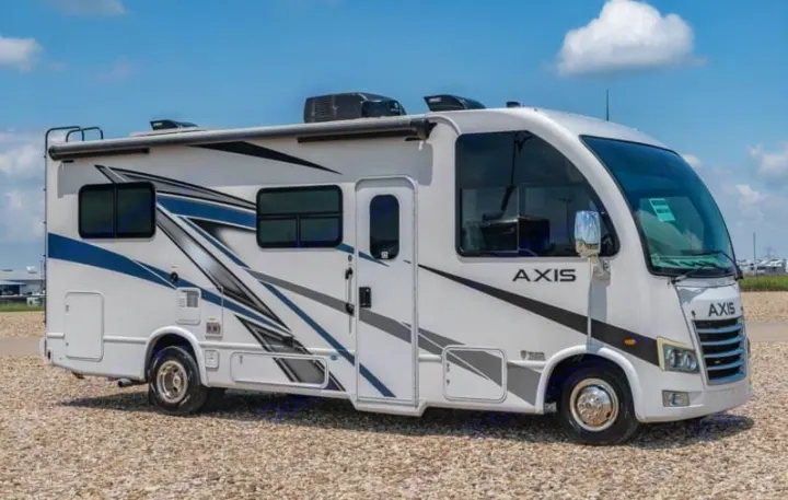 White Axis RV rental with blue/gray graphics on gravel under a sunny sky. Ready for travel adventures.. Axis 24.1 2027