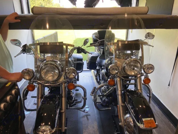 Two touring motorcycles stored side-by-side inside an RV rental toy hauler, ready for adventure.. Forest River Cherokee Wolf Pack 2021