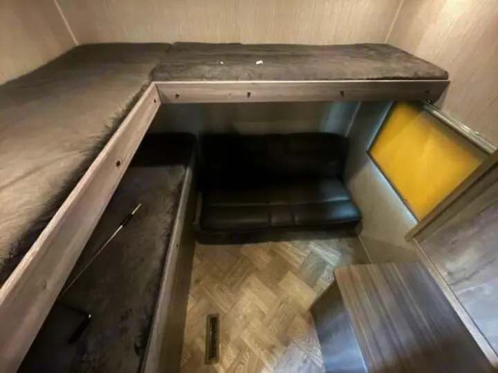Inside this RV rental: an L-shaped bunk bed, sofa, and lower bunk/storage, with a window and wood-look flooring.. Palomino 28bhss 2020