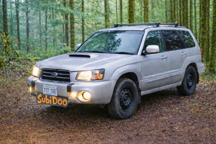 Silver Subaru Forester SUV in a lush forest setting. Ready for rugged adventures, perfect for exploring alongside your rv rental.. Subaru Forester 2007