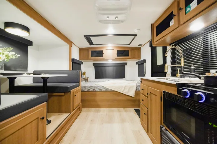 Inside a modern rv rental: dining booth on the left, bed at the back, and kitchen on the right, ready for adventure.. Coachmen Apex Nano 194BHS 2026