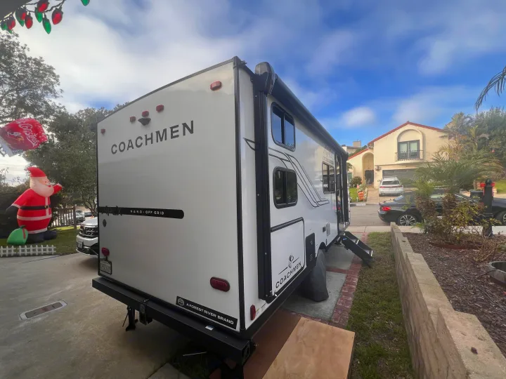 White Coachmen Apex Nano travel trailer, an RV rental, parked in a driveway with an inflatable Santa and Christmas lights.. Coachmen Apex Nano 194BHS 2026