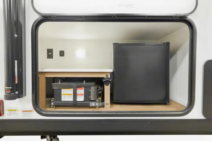 This RV rental's exterior compartment reveals a mini-fridge, power outlet, battery, and bottle opener for easy access.. Coachmen Apex Nano 194BHS 2026